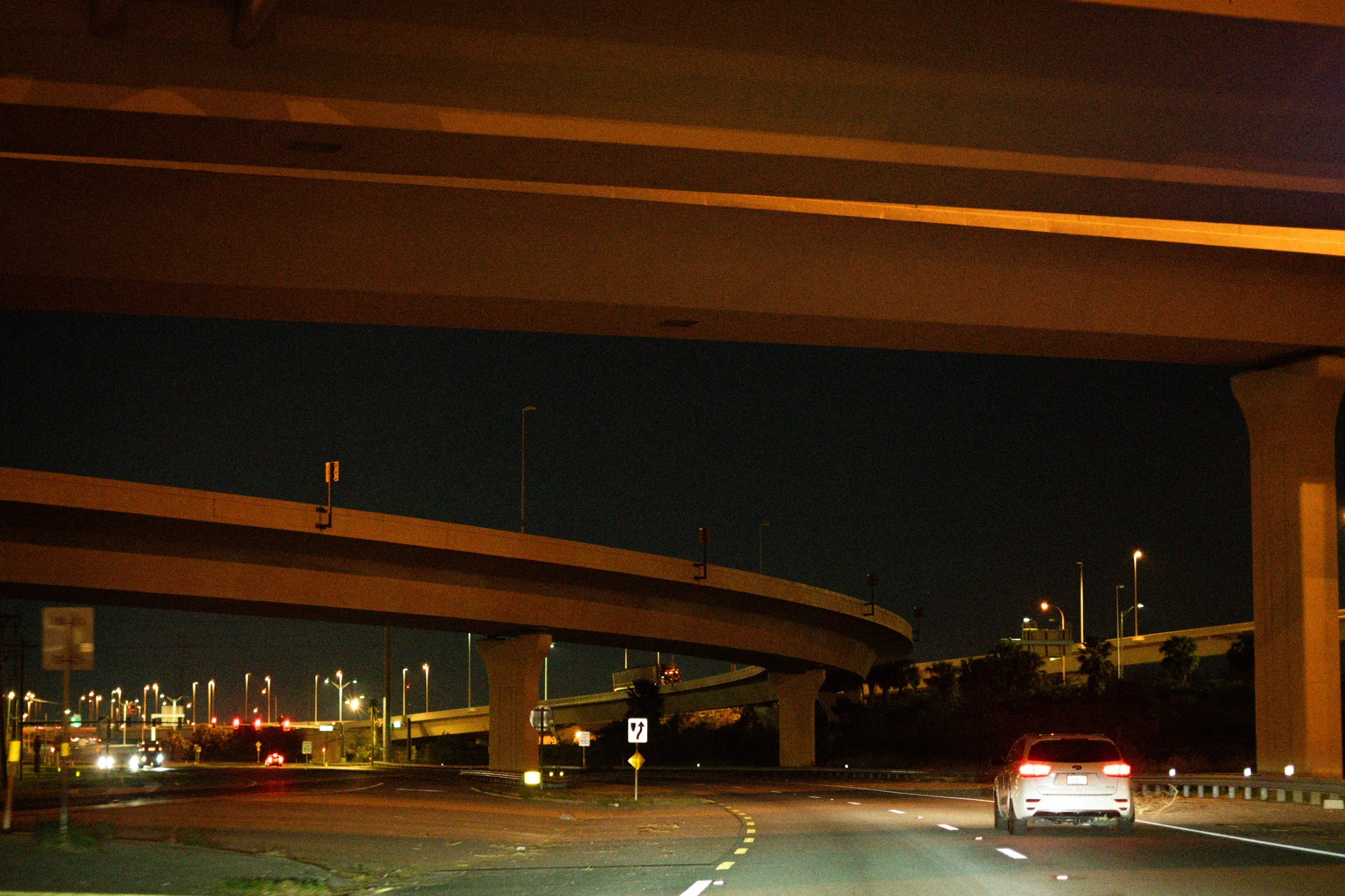 Cars moving beneath a highway overpass at night