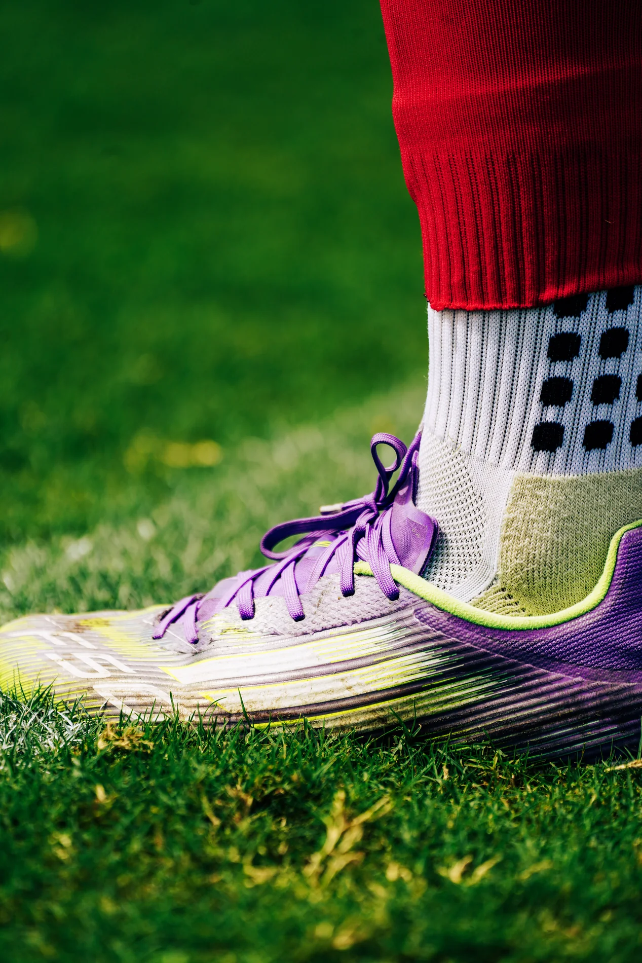 Purple soccer cleat planted in bright green grass