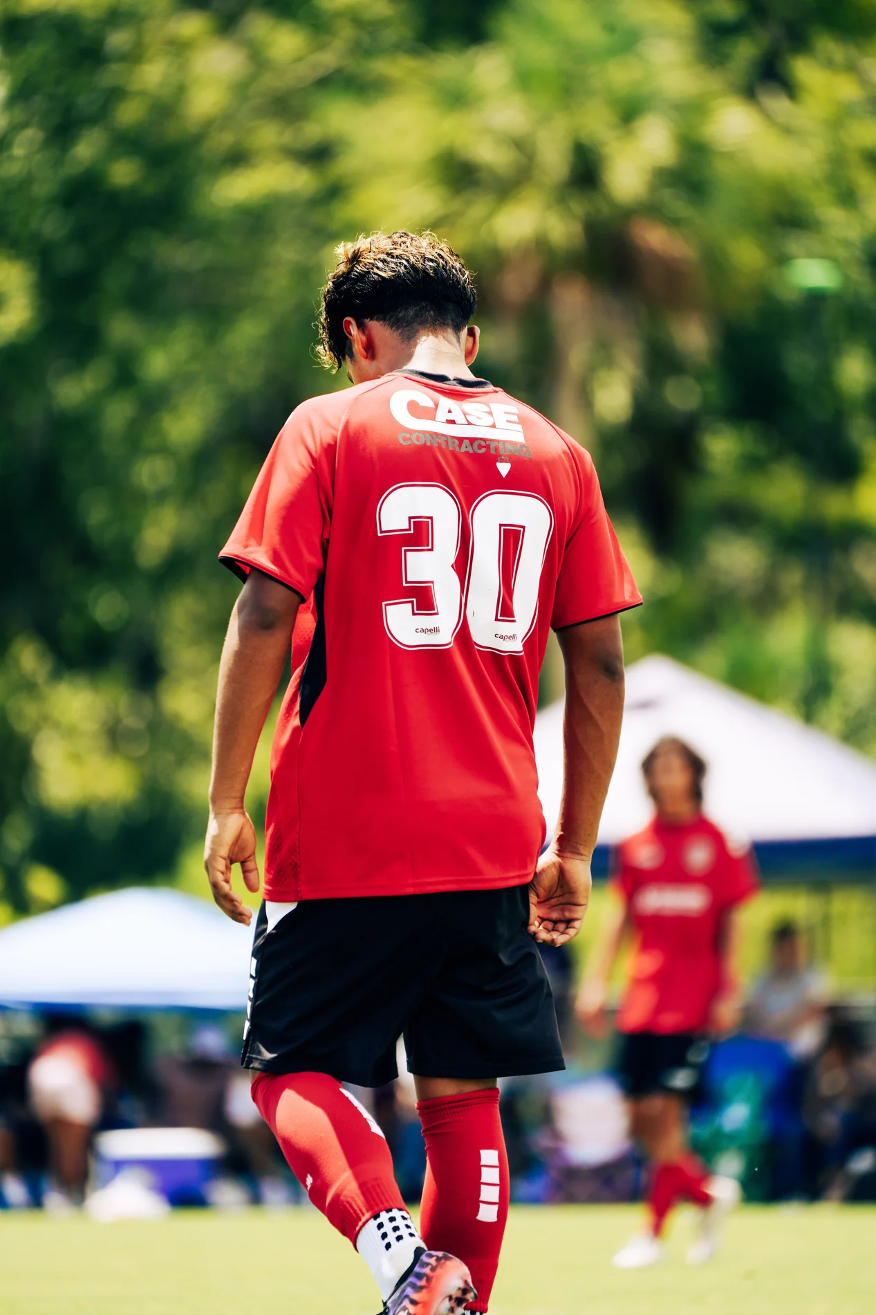 Soccer player in a red number 30 jersey walking onto the field